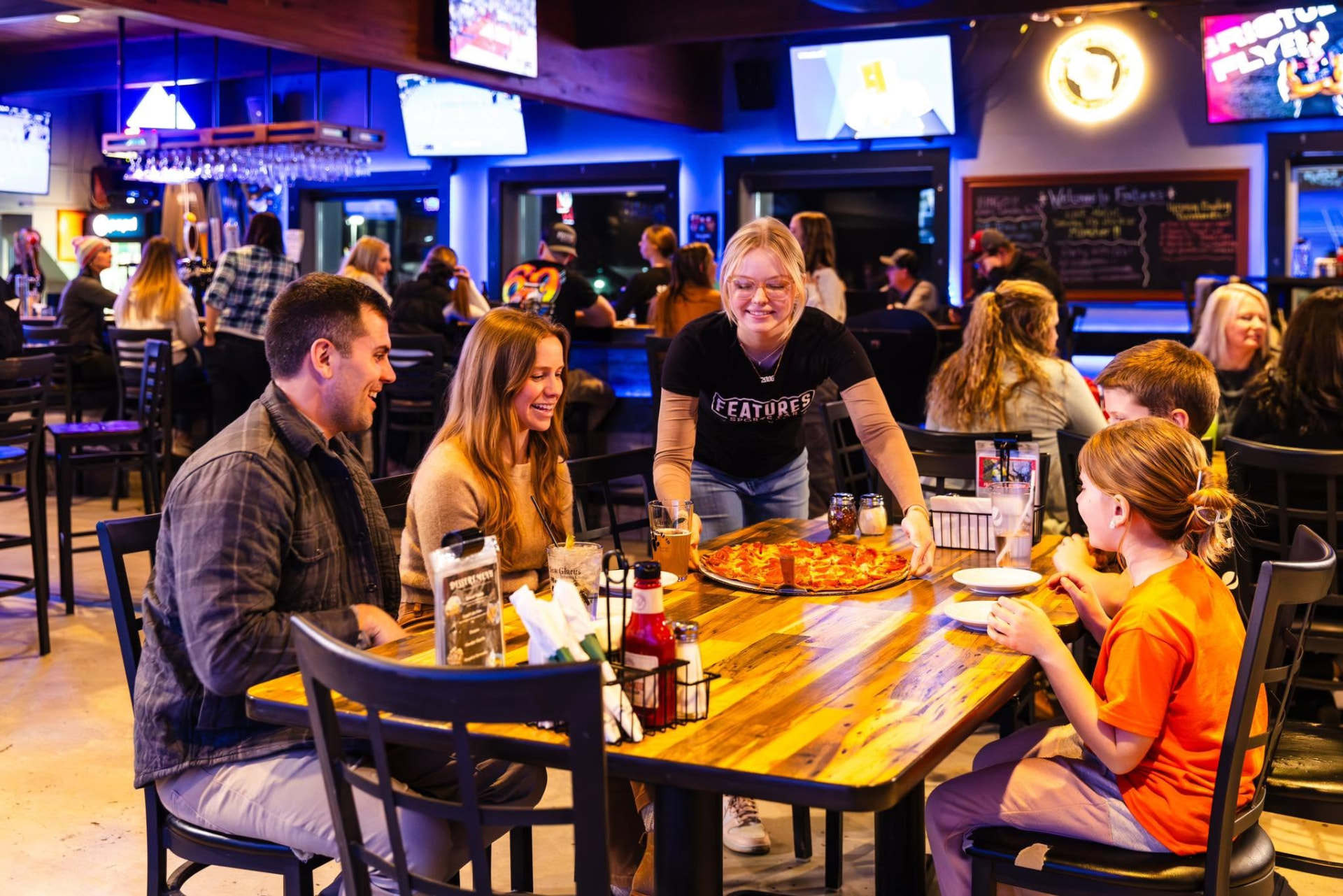 Family sharing pizza at Features Sports Bar & Grill